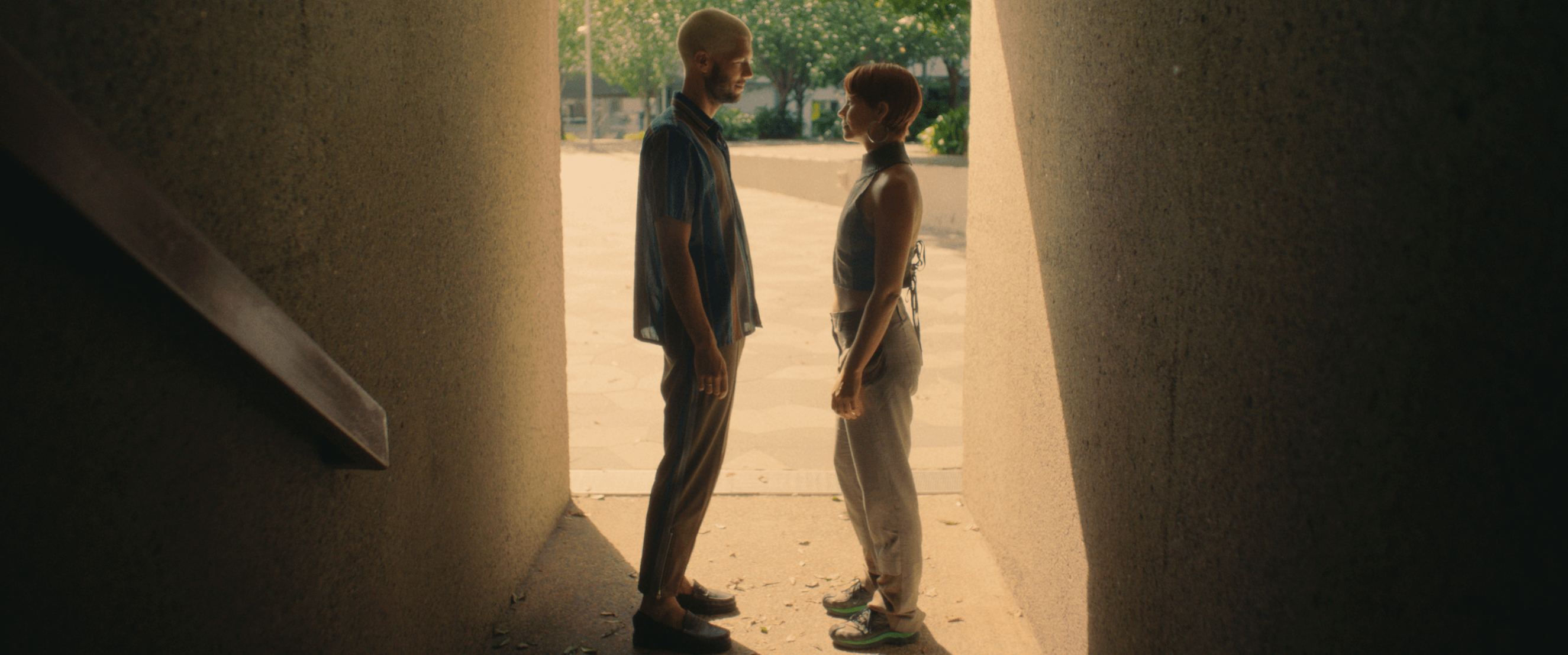 Two young people standing facing each other inside a tunnel.